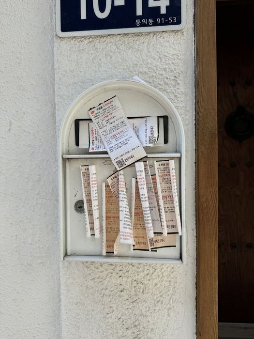Postal notices gathered around a letterbox in Seochon